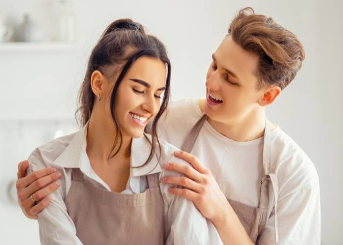 A smiling man and woman stand together in a bright kitchen